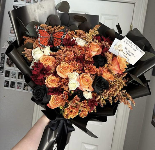 Bouquet of flowers with a butterfly and a card, held by a person.