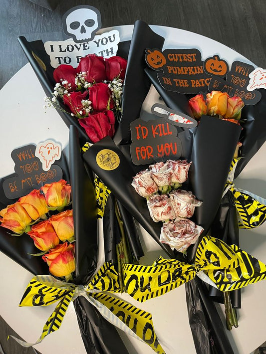 Halloween-themed flower bouquets with decorative text and ribbons on a white surface.